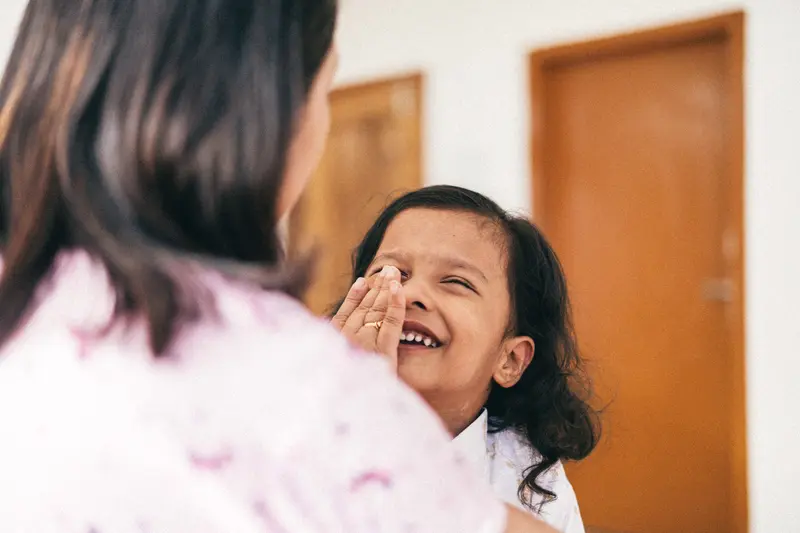 A loving interaction between mother and daughter, capturing laughter and affection indoors.