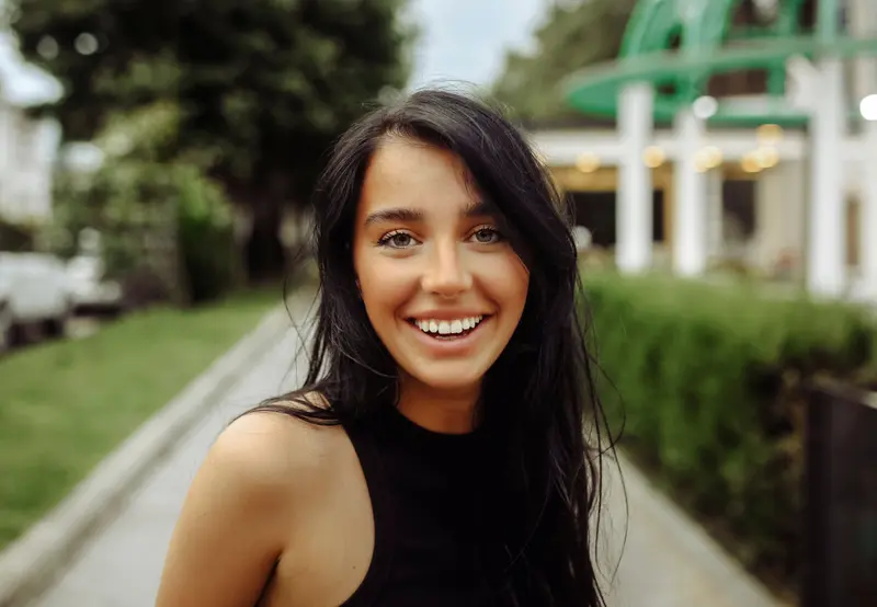 A woman with a wide, even smile outdoors in natural light