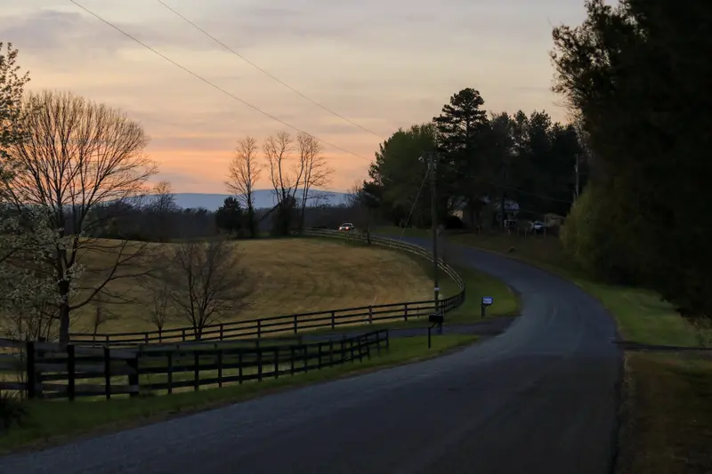 A fence-lined country road at dusk
