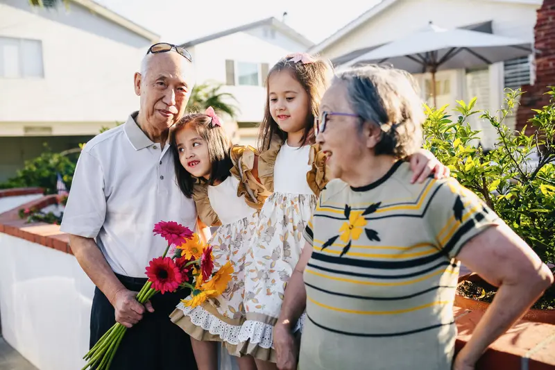 Grandparents and their granddaughters with fresh flowers outside the house