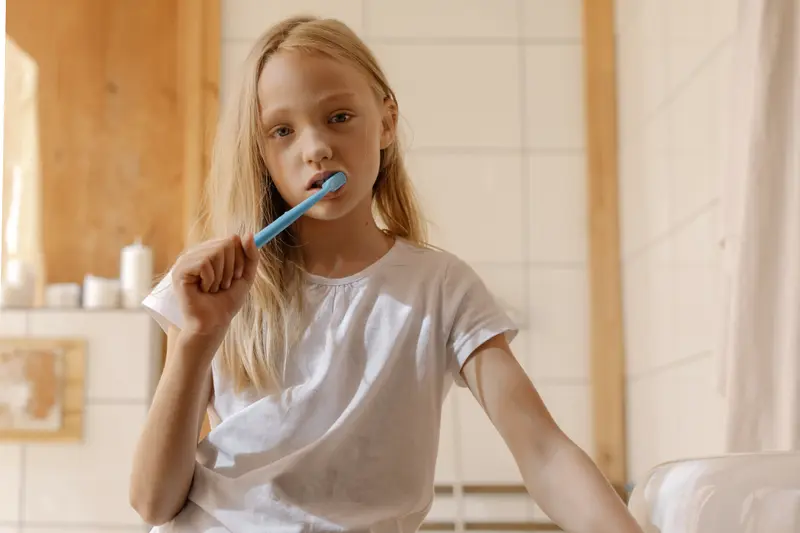 A girl brushing her teeth in a bright bathroom