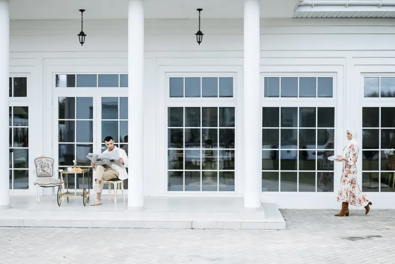 A woman crossing a white colonial porch